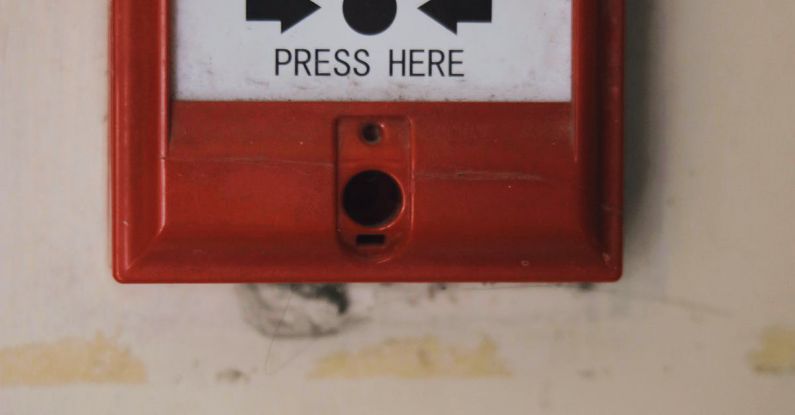 Alarm Systems - Manual emergency red fire alarm system box with push button placed on white shabby wall in light room of building