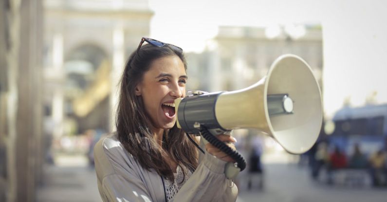 Voice Assistants - Cheerful young woman screaming into megaphone