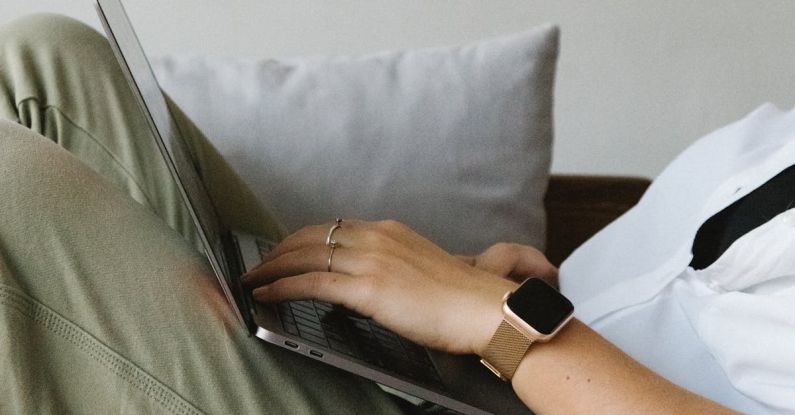 Smart Locks - Side view of crop unrecognizable female freelancer in casual clothes and smartwatch lying on comfortable sofa and working remotely on laptop